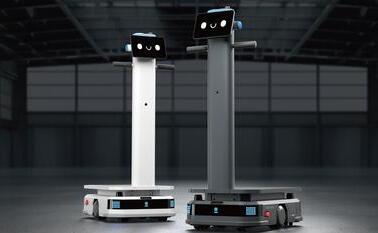Zwei T300 Roboter in einem Raum mit einer grossen weissen Maschine, die für den Transport schwerer Lasten konzipiert sind.