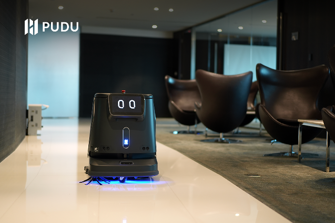 Der schwarze Pudu Robotics CC1 reinigt den Boden in der Hotellobby.