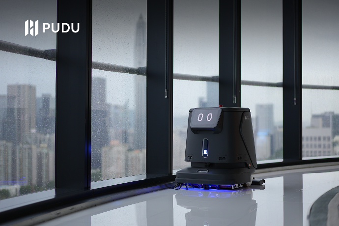 Der schwarze Pudu Robotic CC1 reinigt den Boden neben dem Gebäudefenster.