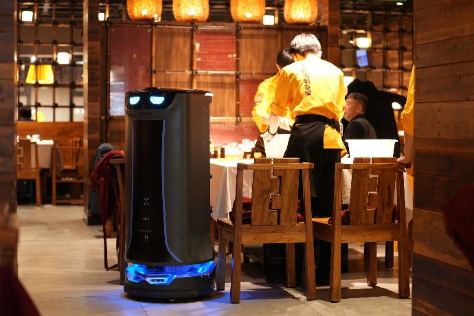 Pudu Robotik HolaBot serviert Essen in einem Restaurant.