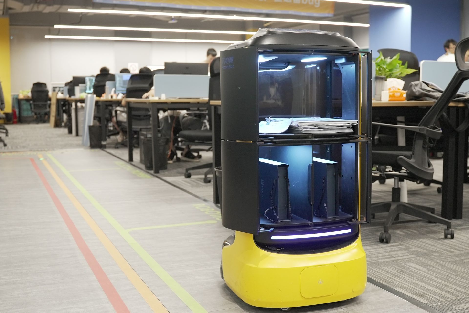 Ein gelber und schwarzer Roboter in einem Büro.