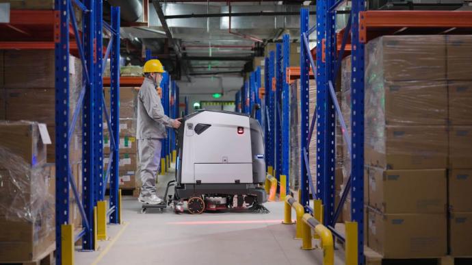 Autonomer Pudu BG1 Reinigungsroboter mit Aufsteh‑Mitfahr‑Modus im Logistik‑ und Lagerbereich